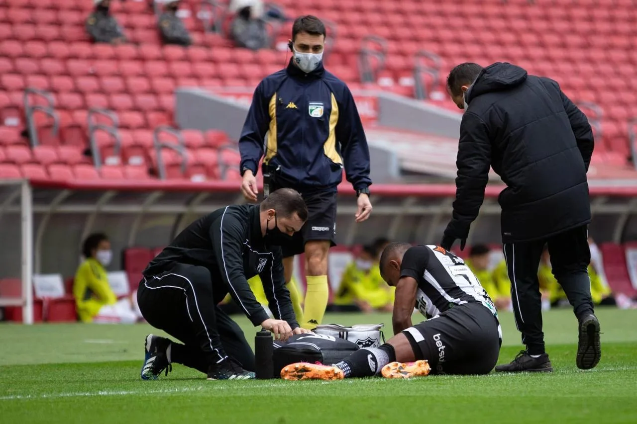 Dr. Rodrigo Oliveira atendendo atleta dentro de campo durante jogo profissional